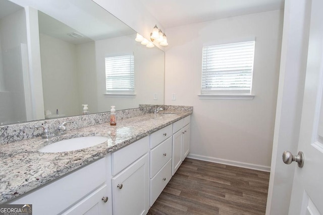 bathroom featuring double vanity, baseboards, a sink, and wood finished floors