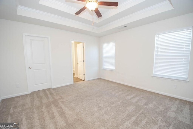 unfurnished bedroom featuring light carpet, baseboards, ornamental molding, and a raised ceiling