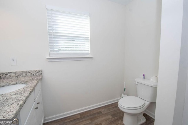 bathroom featuring toilet, baseboards, wood finished floors, and vanity