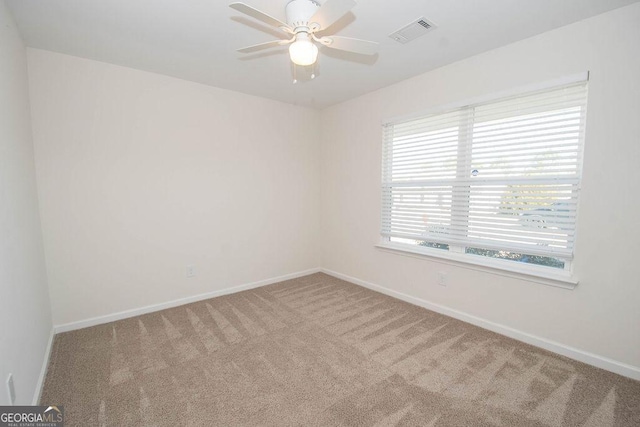 carpeted empty room with a ceiling fan, visible vents, and baseboards