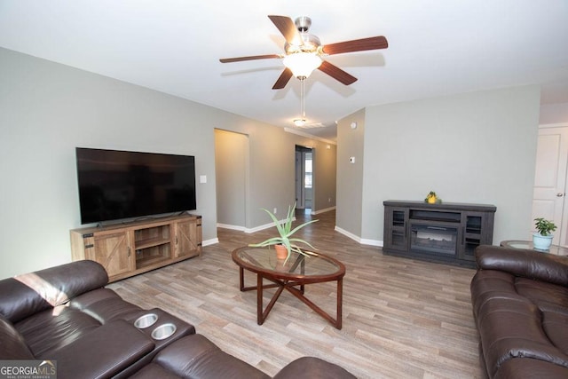 living area with light wood-style flooring, baseboards, and ceiling fan