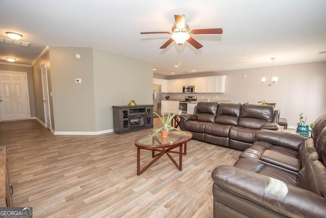 living area featuring crown molding, recessed lighting, light wood-style flooring, baseboards, and ceiling fan with notable chandelier