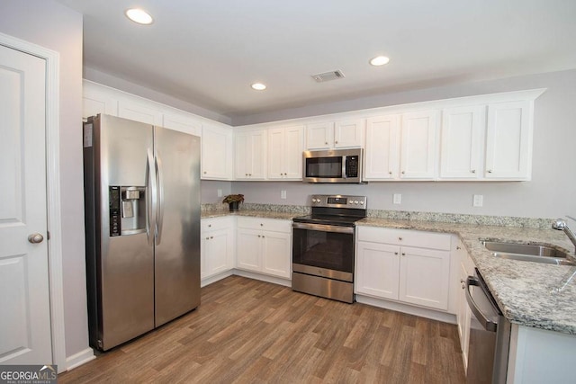 kitchen featuring a sink, visible vents, white cabinets, appliances with stainless steel finishes, and light wood finished floors