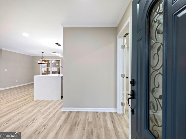 entrance foyer featuring light wood-style floors, baseboards, a chandelier, and crown molding