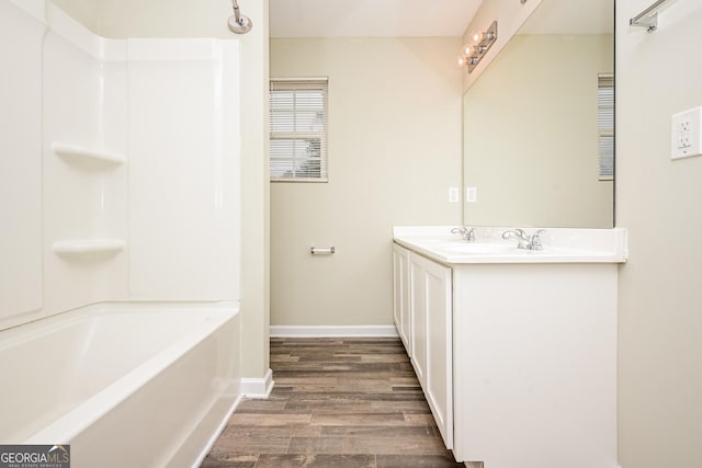 bathroom featuring a sink, wood finished floors, baseboards, tub / shower combination, and double vanity