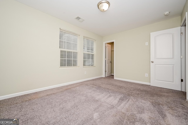 carpeted spare room featuring visible vents and baseboards