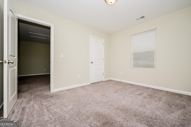 unfurnished bedroom featuring a closet, visible vents, a spacious closet, light carpet, and baseboards