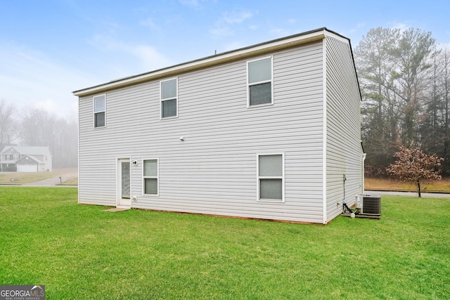 rear view of house featuring a lawn and central air condition unit