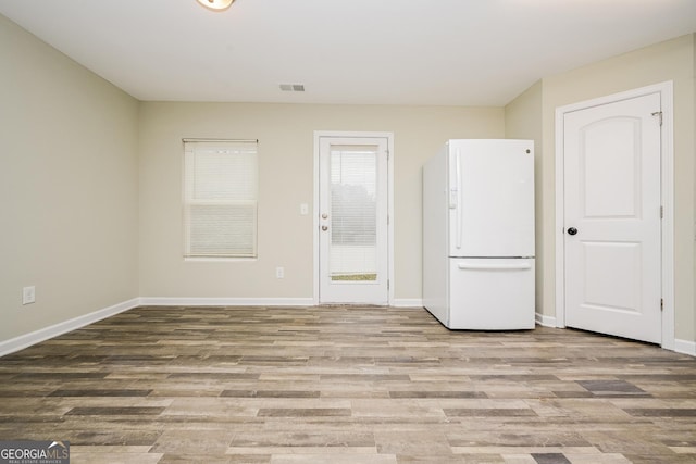 empty room with baseboards, visible vents, and light wood finished floors