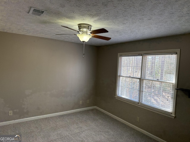 carpeted empty room featuring visible vents, ceiling fan, a textured ceiling, and baseboards