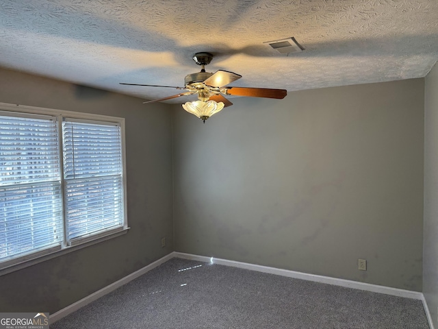 unfurnished room with ceiling fan, a textured ceiling, visible vents, baseboards, and carpet