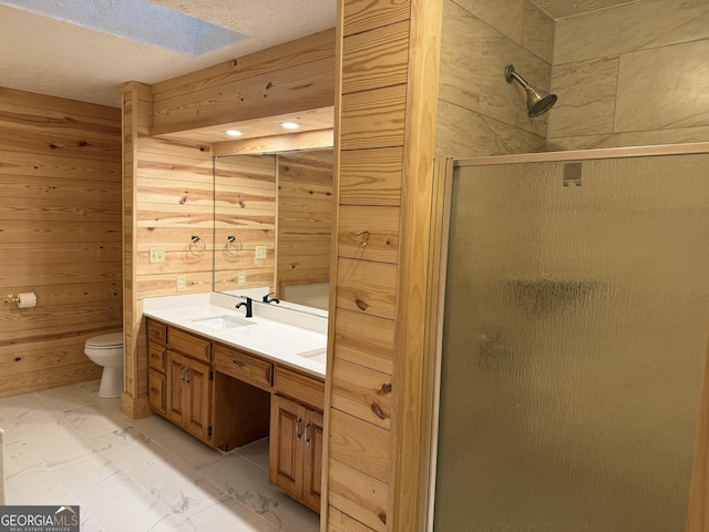 bathroom featuring wood walls, a shower stall, marble finish floor, and a sink