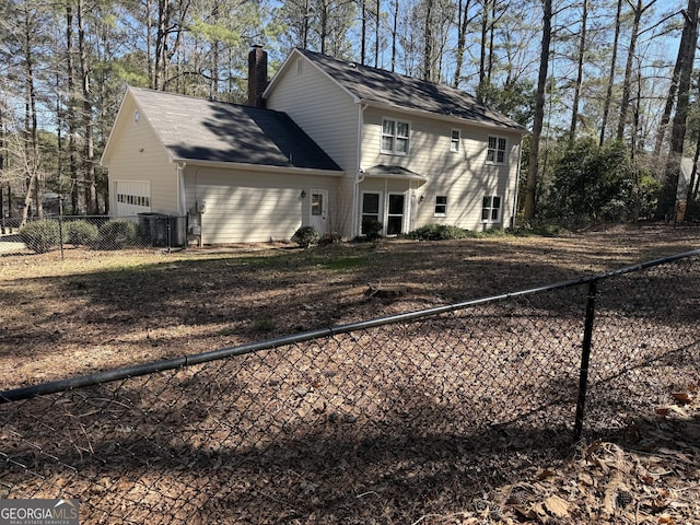 view of front of house featuring a chimney, an attached garage, and fence