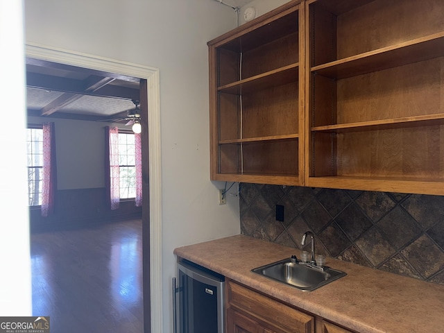 bar featuring wood finished floors, a sink, a ceiling fan, backsplash, and indoor wet bar