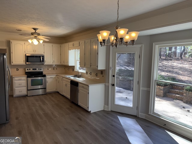 kitchen with stainless steel appliances, a sink, white cabinets, light countertops, and decorative light fixtures