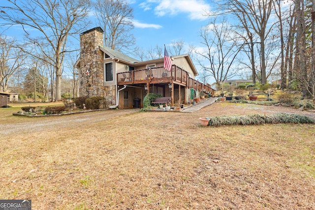 rear view of house with a lawn, a chimney, and a wooden deck