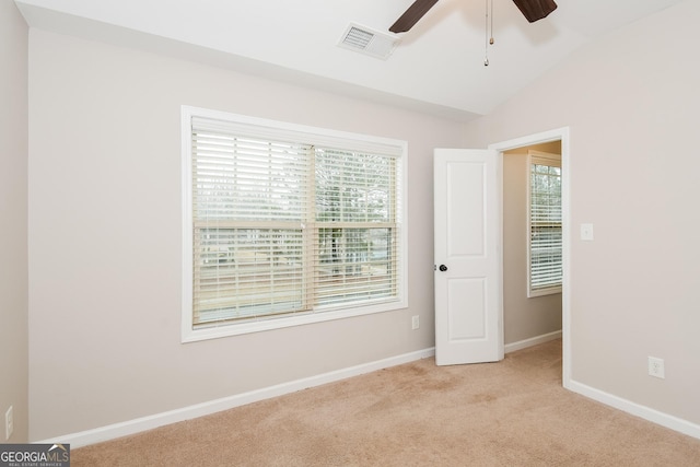 unfurnished bedroom with lofted ceiling, light colored carpet, visible vents, and baseboards