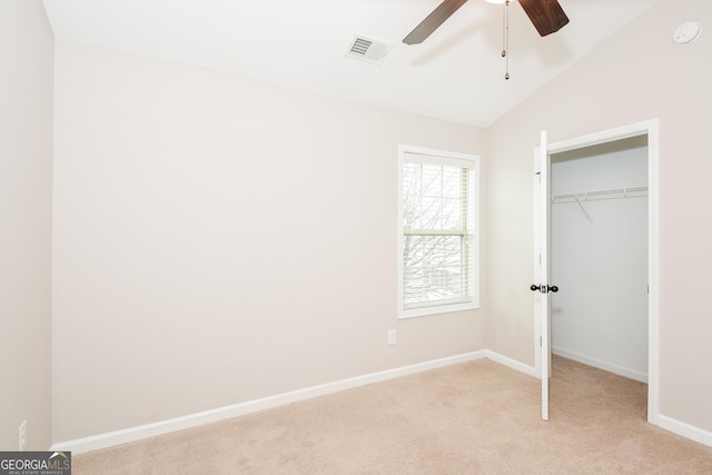 unfurnished bedroom with light carpet, baseboards, visible vents, lofted ceiling, and a closet