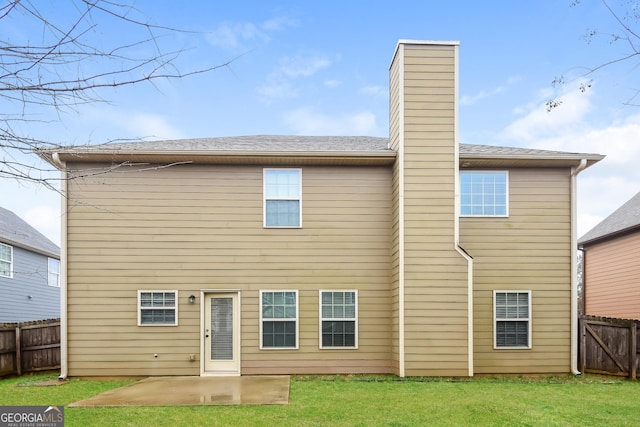 back of house with a patio area, a chimney, fence, and a lawn