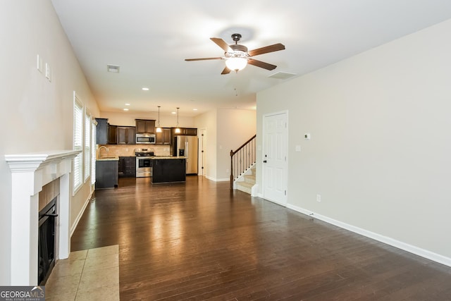 living area featuring dark wood-style flooring, visible vents, stairway, and a tiled fireplace