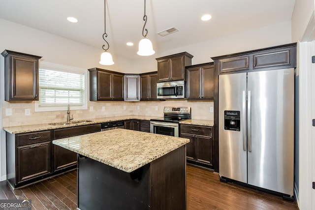 kitchen with visible vents, a kitchen island, hanging light fixtures, stainless steel appliances, and a sink