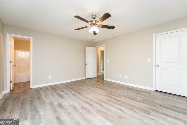 unfurnished bedroom featuring baseboards, ceiling fan, ensuite bathroom, and light wood-style floors