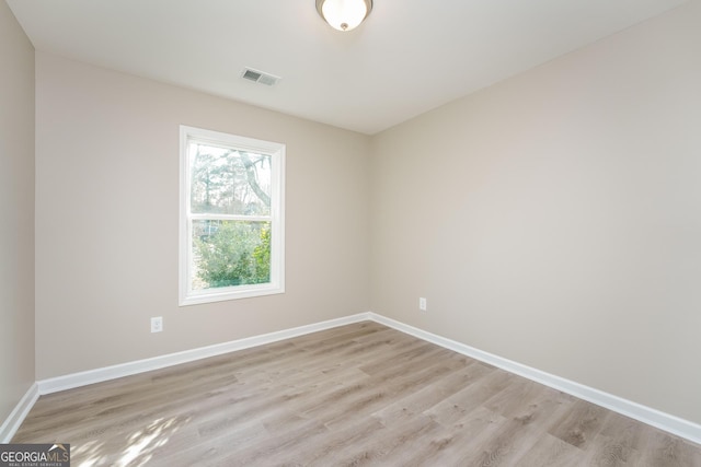 empty room featuring visible vents, light wood-style flooring, and baseboards