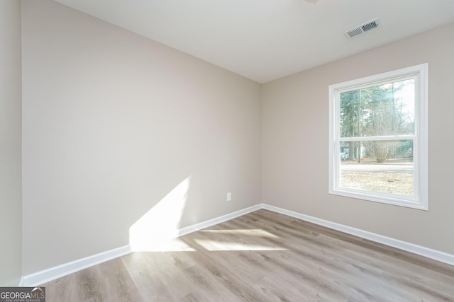 empty room featuring light wood-type flooring, baseboards, and visible vents