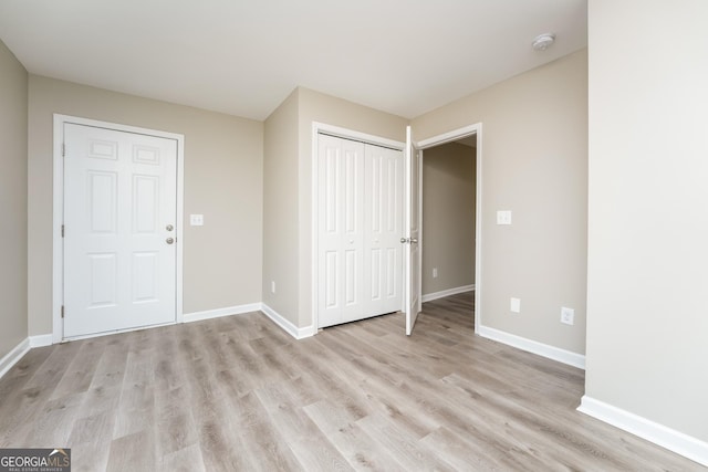 interior space featuring a closet, baseboards, and light wood finished floors