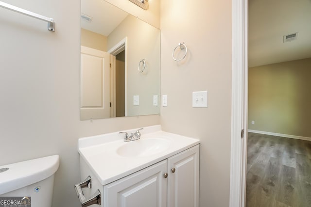 bathroom featuring toilet, wood finished floors, vanity, and visible vents