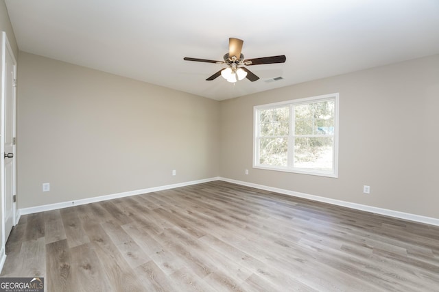 empty room featuring ceiling fan, light wood finished floors, visible vents, and baseboards