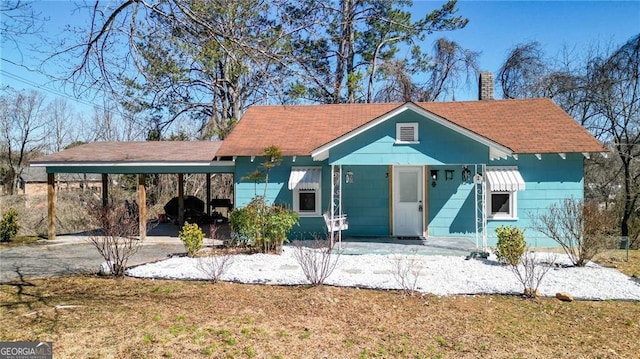 view of front facade with driveway, a chimney, and an attached carport