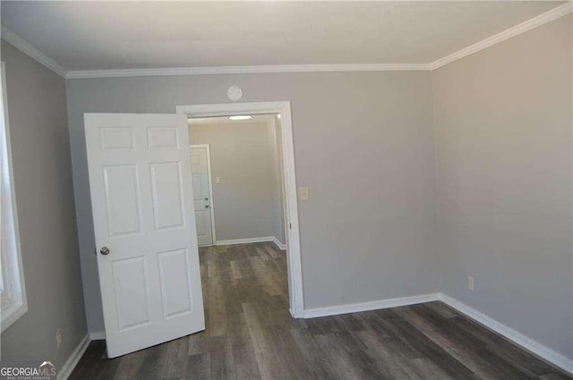 unfurnished room featuring dark wood-style floors, ornamental molding, and baseboards