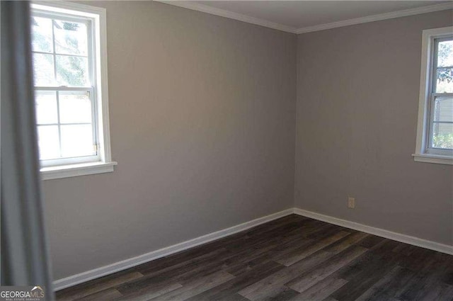 empty room featuring crown molding, dark wood finished floors, and baseboards