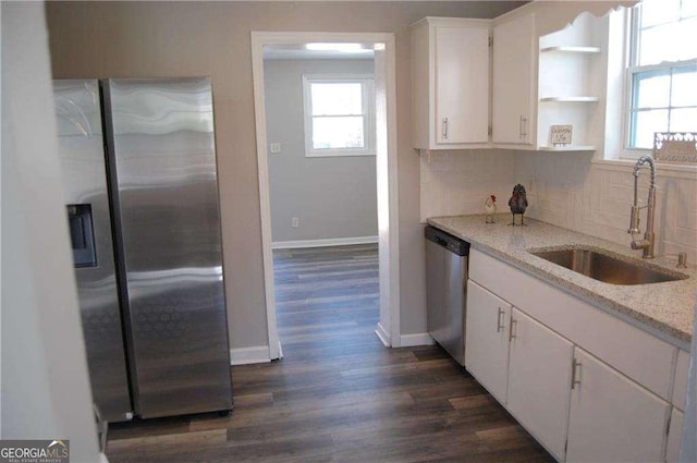 kitchen with stainless steel appliances, a sink, white cabinetry, light stone countertops, and plenty of natural light