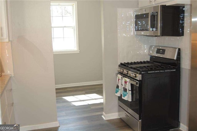 kitchen with baseboards, tasteful backsplash, appliances with stainless steel finishes, and wood finished floors