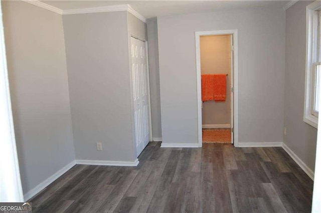 unfurnished bedroom with ornamental molding, a closet, dark wood finished floors, and baseboards