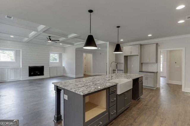 kitchen featuring a center island with sink, open floor plan, decorative light fixtures, gray cabinets, and a sink