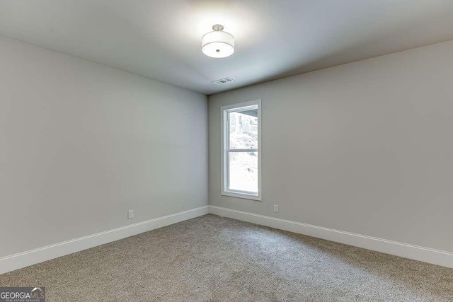 spare room featuring carpet floors, visible vents, and baseboards