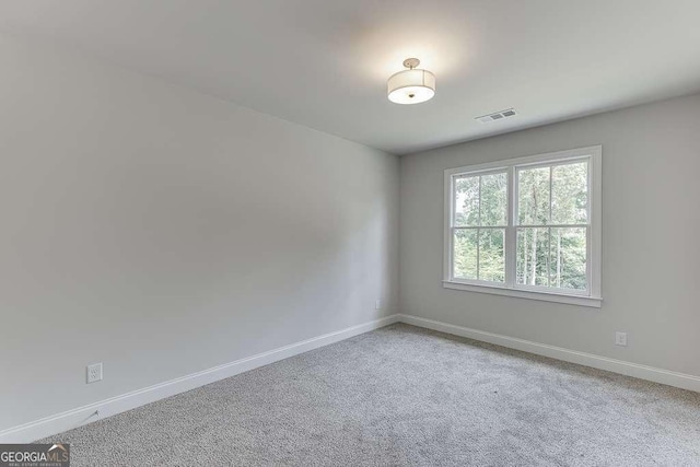 carpeted spare room featuring visible vents and baseboards