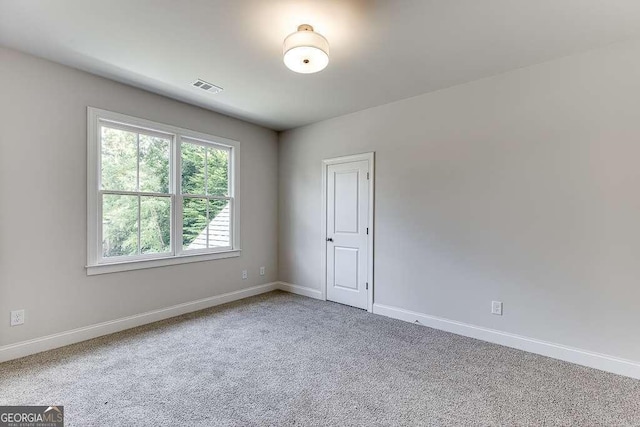 carpeted spare room featuring baseboards and visible vents