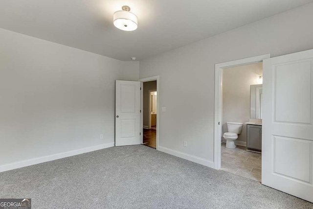 unfurnished bedroom with light carpet, connected bathroom, and baseboards