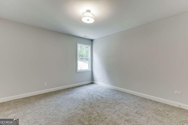 empty room with carpet floors, visible vents, and baseboards