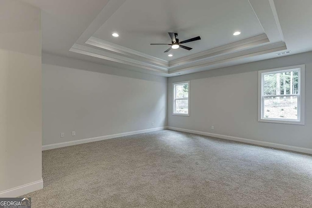 unfurnished room featuring a tray ceiling, recessed lighting, light colored carpet, visible vents, and baseboards