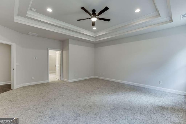 empty room with carpet flooring, a raised ceiling, and visible vents