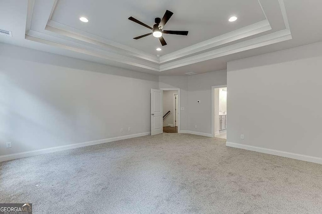 spare room featuring light carpet, baseboards, a tray ceiling, and ceiling fan