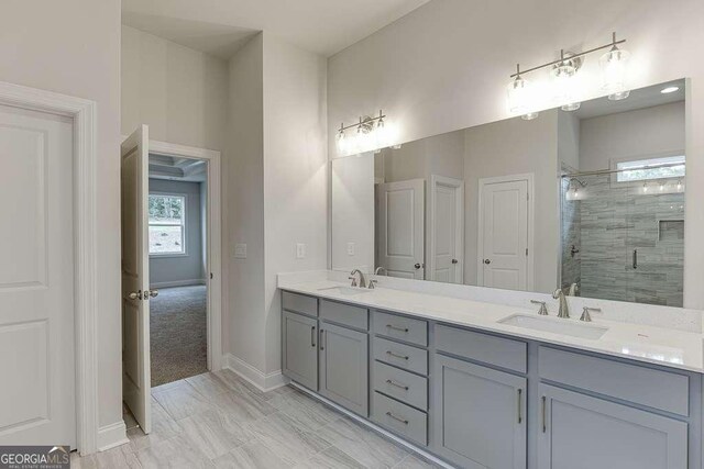 bathroom with double vanity, a stall shower, a sink, and baseboards