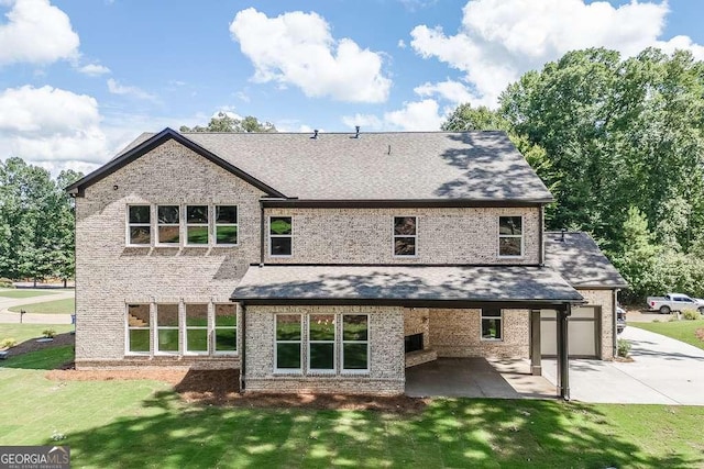 rear view of property with a yard, a patio, driveway, and an attached garage