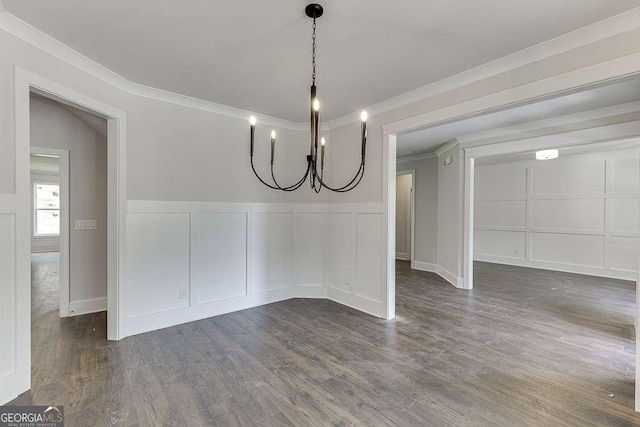 unfurnished dining area featuring a wainscoted wall, crown molding, a decorative wall, and dark wood-style flooring