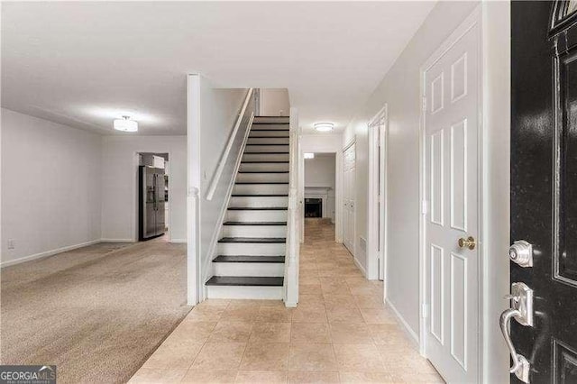 stairs featuring tile patterned flooring, a fireplace, baseboards, and carpet flooring